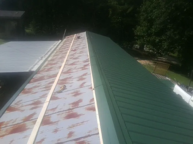 Old rusted panels beside newly installed green metal roofing — Wind Damage Roof Repair by Roofing Brothers in Pendleton